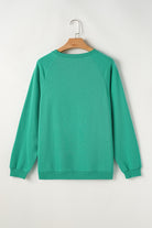 Aqua crew neck pullover shirt with a classic style, made from polyester and cotton blend, hanging on a wooden hanger.