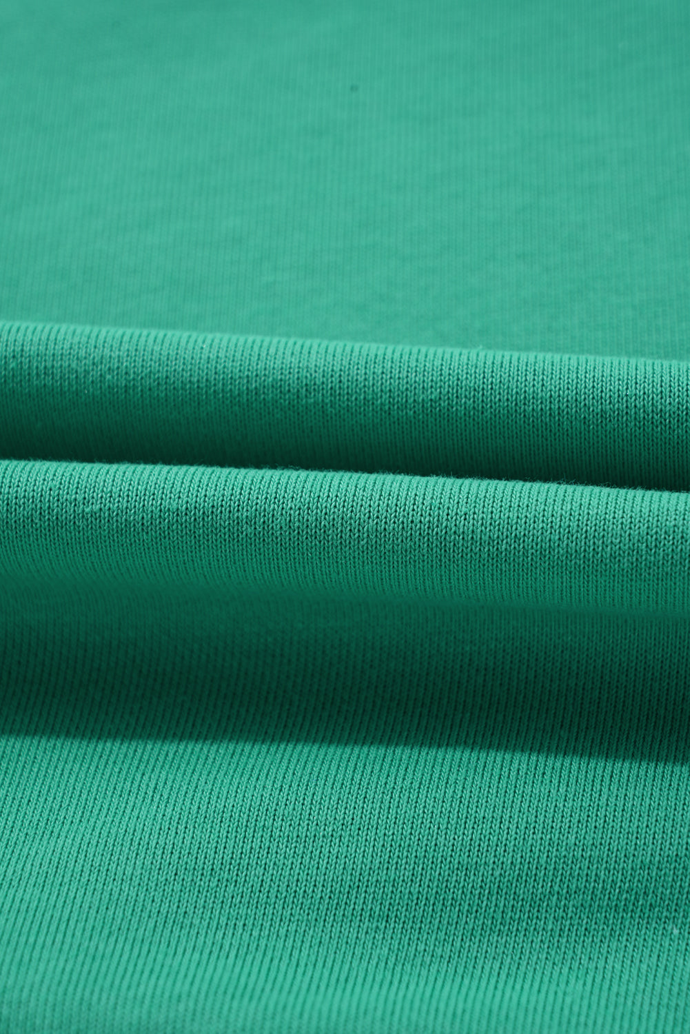 Close-up view of aqua fabric texture, showcasing the knit detail of the Upward Trends Top in a vibrant shade.