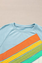 Sky blue crewneck pullover with rainbow color-block stripes and dynamic visual effect, perfect for casual wear.