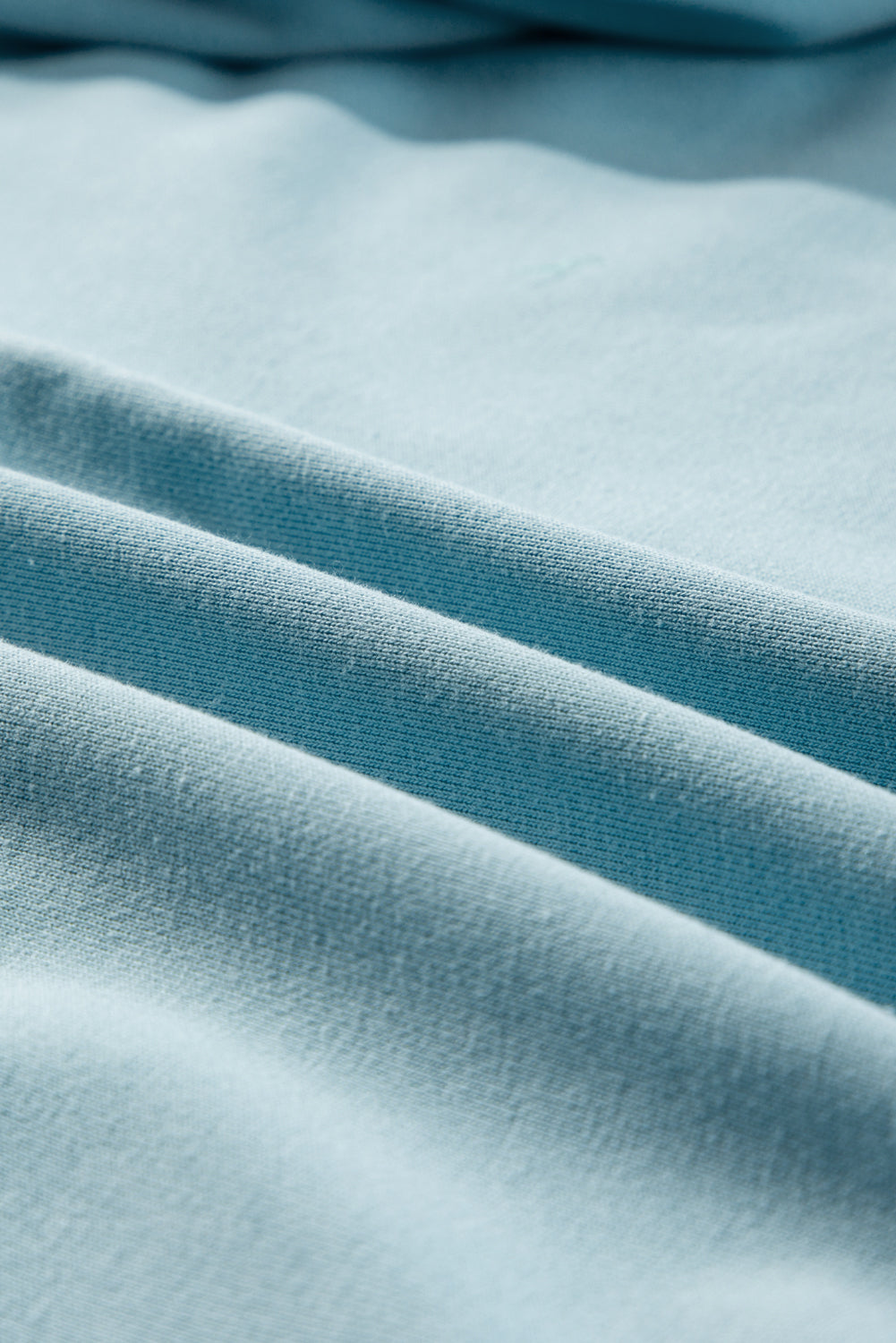 Close-up of sky blue fabric texture, highlighting soft material and vibrant color of the UPWARD TRENDS TOP made of polyester and cotton.