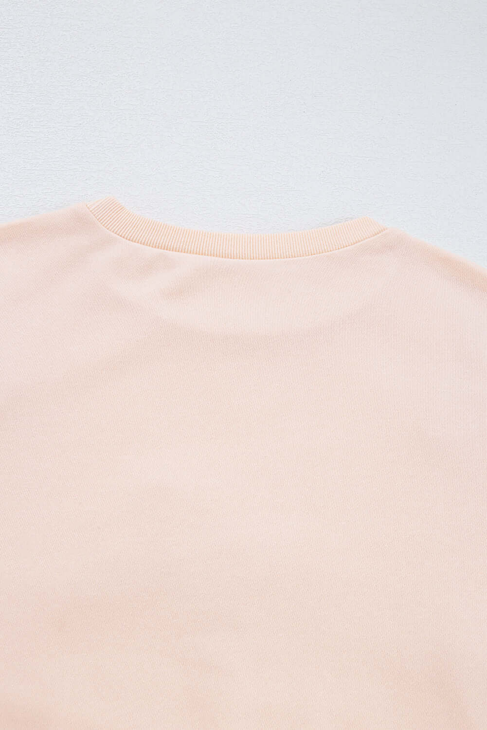 Back view of The Bowtique beige pullover showcasing soft fabric and round neckline.