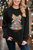 Woman wearing a Painted Christmas Tree sweatshirt with animal-print bow, festive design, perfect for holiday celebrations.