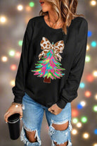 Festive sweatshirt with colorful Christmas tree and animal-print bow, paired with ripped jeans for holiday style.