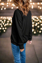 Woman wearing a black sweatshirt with blurred festive lights in the background