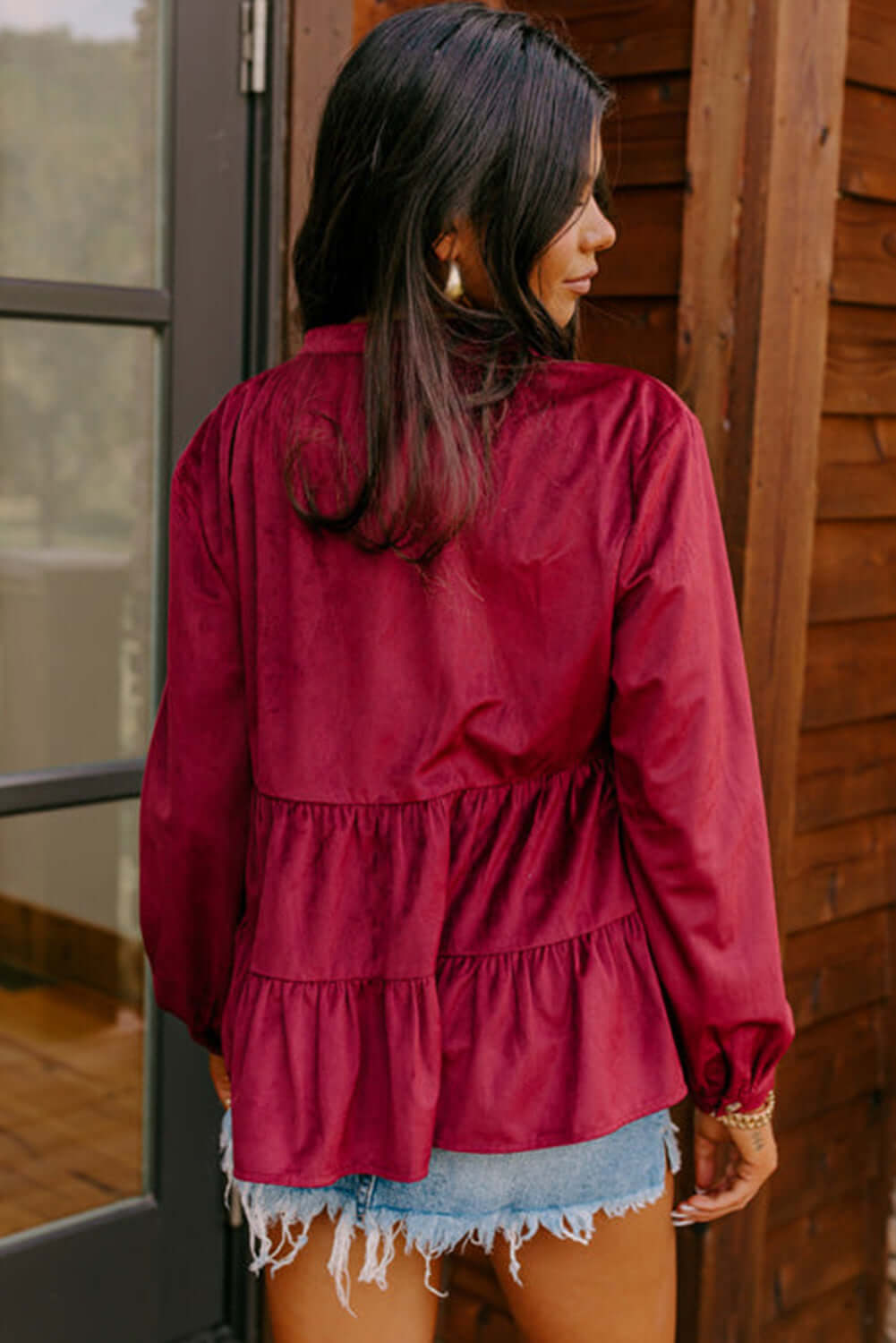 Woman wearing burgundy State of Grace top with tiered ruffle design and O neck collar, showcasing the back view.