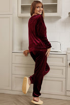 Woman in velvet wine two-piece lounge set with long sleeves and drawstring pants in a kitchen setting.