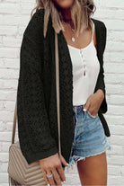 Woman wearing the Café Date Cardigan in jet black over a white tank top and denim shorts, styled for a casual look.