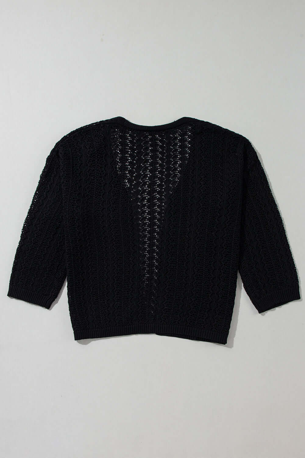 Back view of the Café Date Cardigan in jet black, featuring solid cable knit and chic hollow-out details.