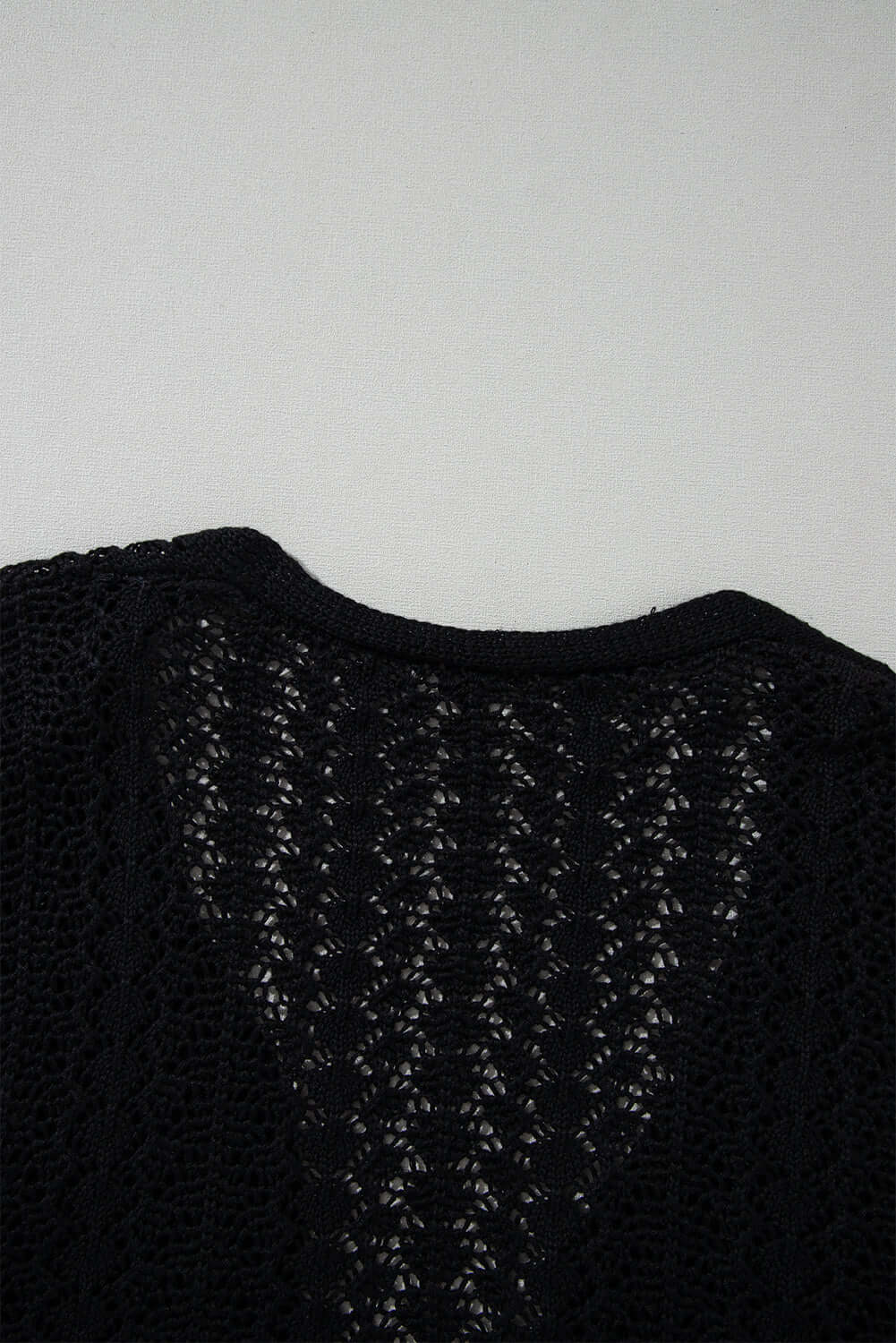 Back view of a Café Date Cardigan in jet black showing hollow-out detail and soft cable knit pattern.