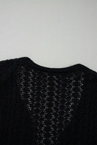 Back view of a Café Date Cardigan in jet black showing hollow-out detail and soft cable knit pattern.