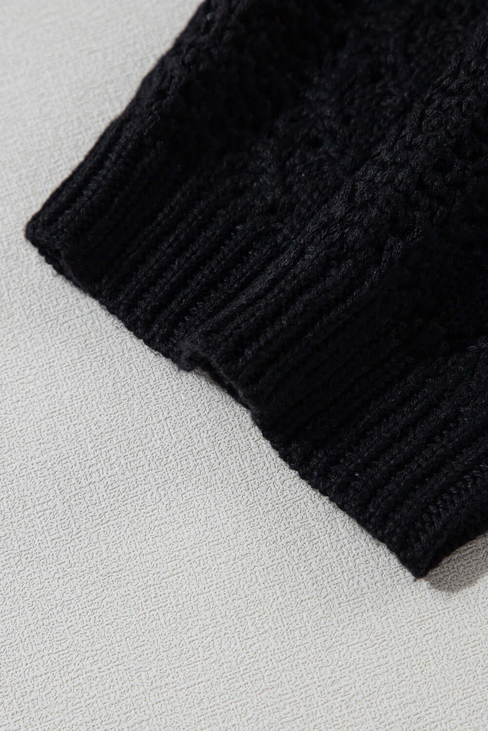 Close-up of the cable knit texture of the jet black Café Date Cardigan, highlighting its cozy design.