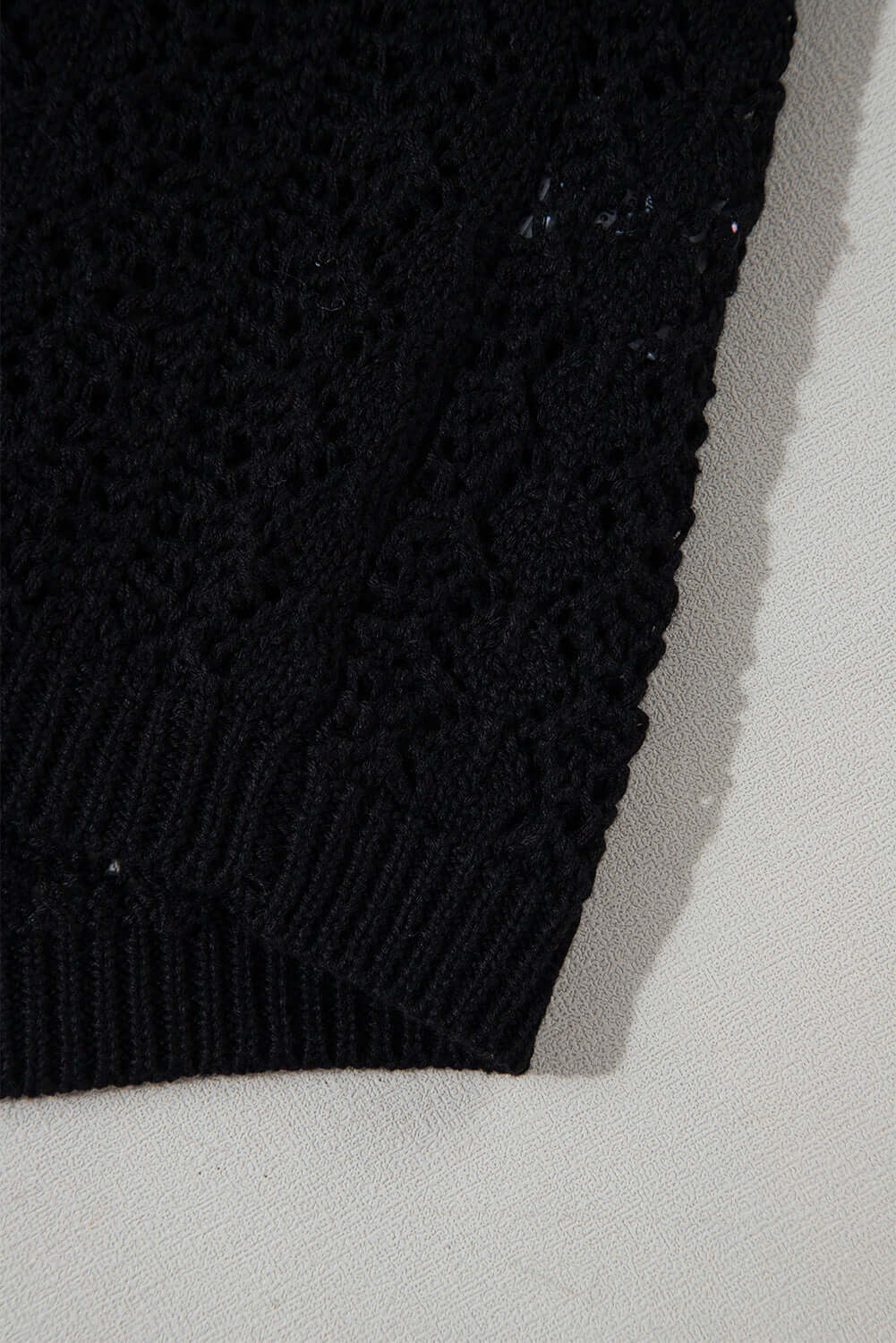 Close-up of black Café Date Cardigan showcasing solid cable knit and hollow-out details.