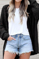 Model wearing Blackout Bliss Cardigan with white tee and denim shorts, showcasing stylish summer outfit.
