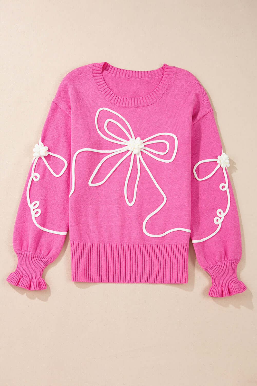 Pink sweater with corded bows and ruffled cuffs, featuring a dropped shoulder design for a trendy and comfortable look.