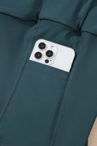 Close-up of sea green skort pocket holding a smartphone, showcasing functional and stylish design.