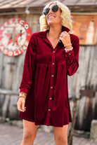 Woman wearing vibrant velvet red berry dress with crinkled texture, collared neck, front buttons, and chest pockets in a relaxed fit.