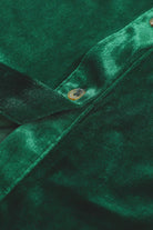 Close-up of evergreen velvet fabric with button detail from Vivian-Lu dress, highlighting luxurious texture and vibrant color.