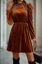 Elegant chestnut brown velvet dress with long gigot sleeves and gathered waist from Vivian-Lu, styled with black handbag.