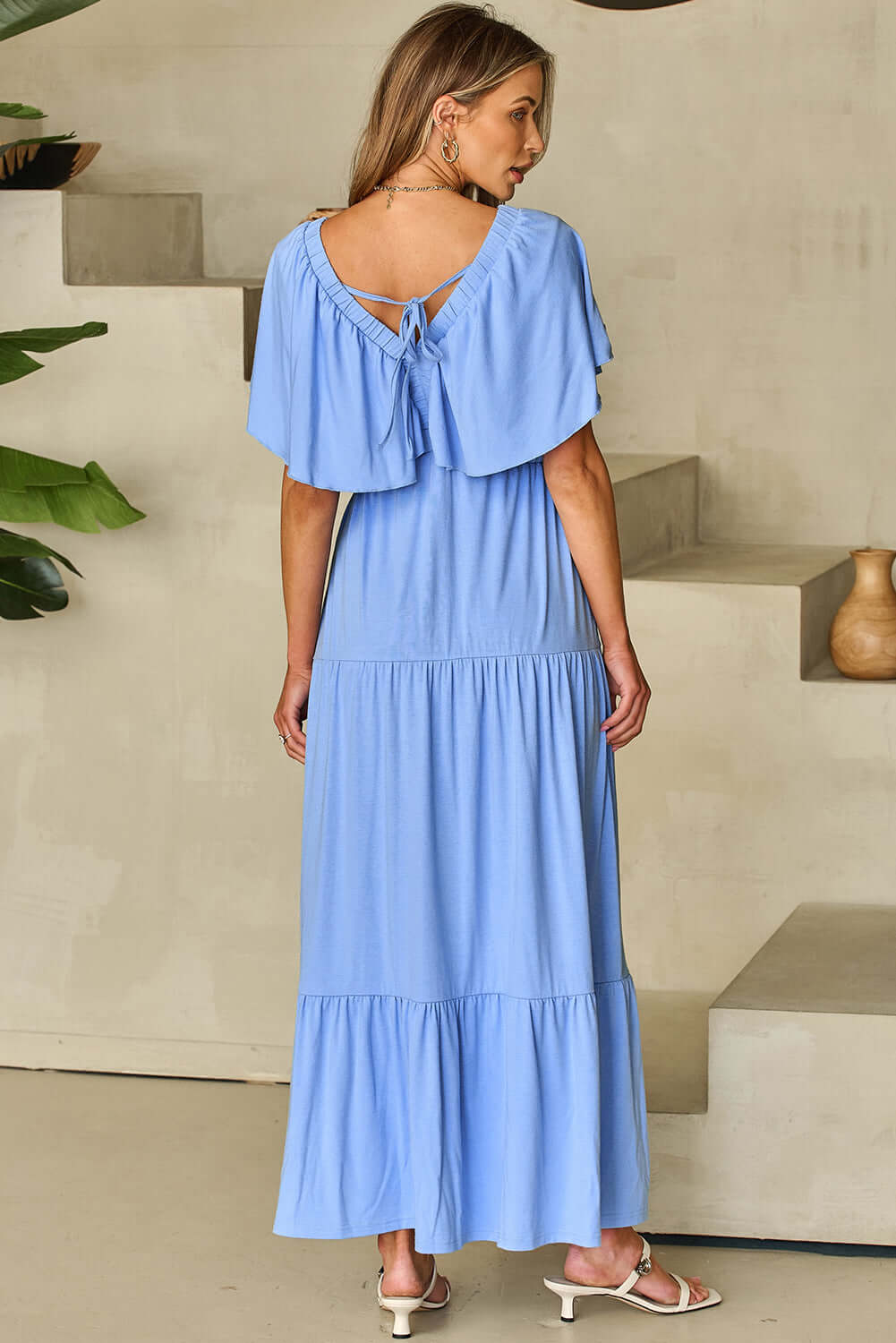 Back view of Dreamfield Days Maxi Dress in sky blue, featuring flutter sleeves and a tied neckline.
