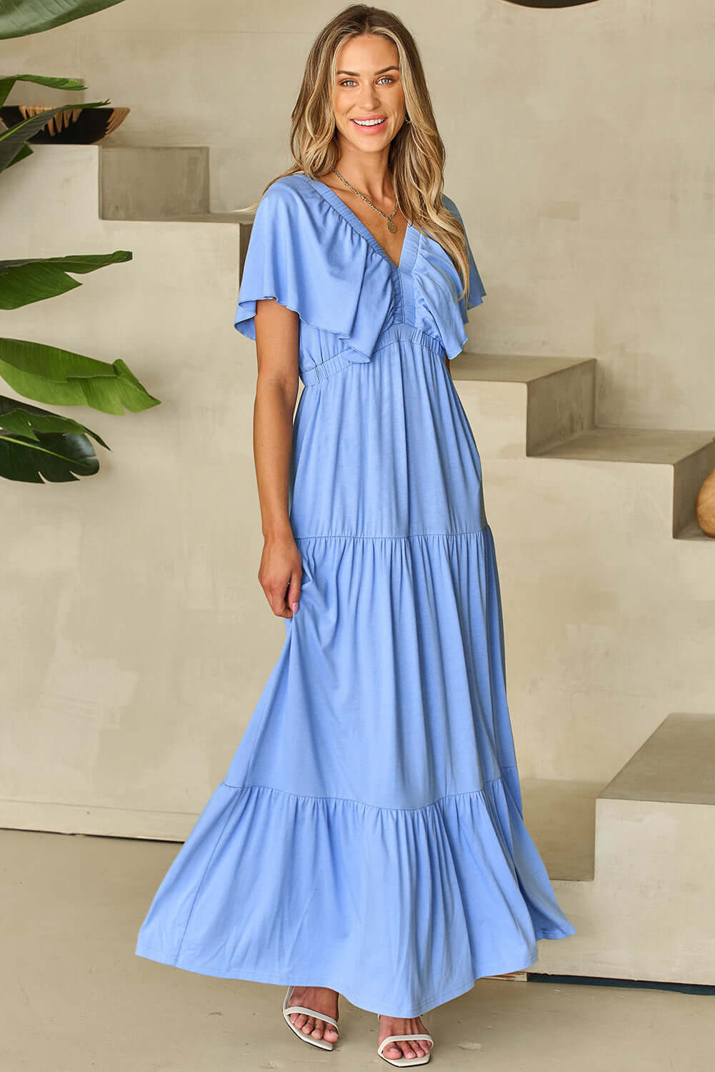 Model in a serene sky blue maxi dress with flutter sleeves, perfect for summer brunches and garden walks.