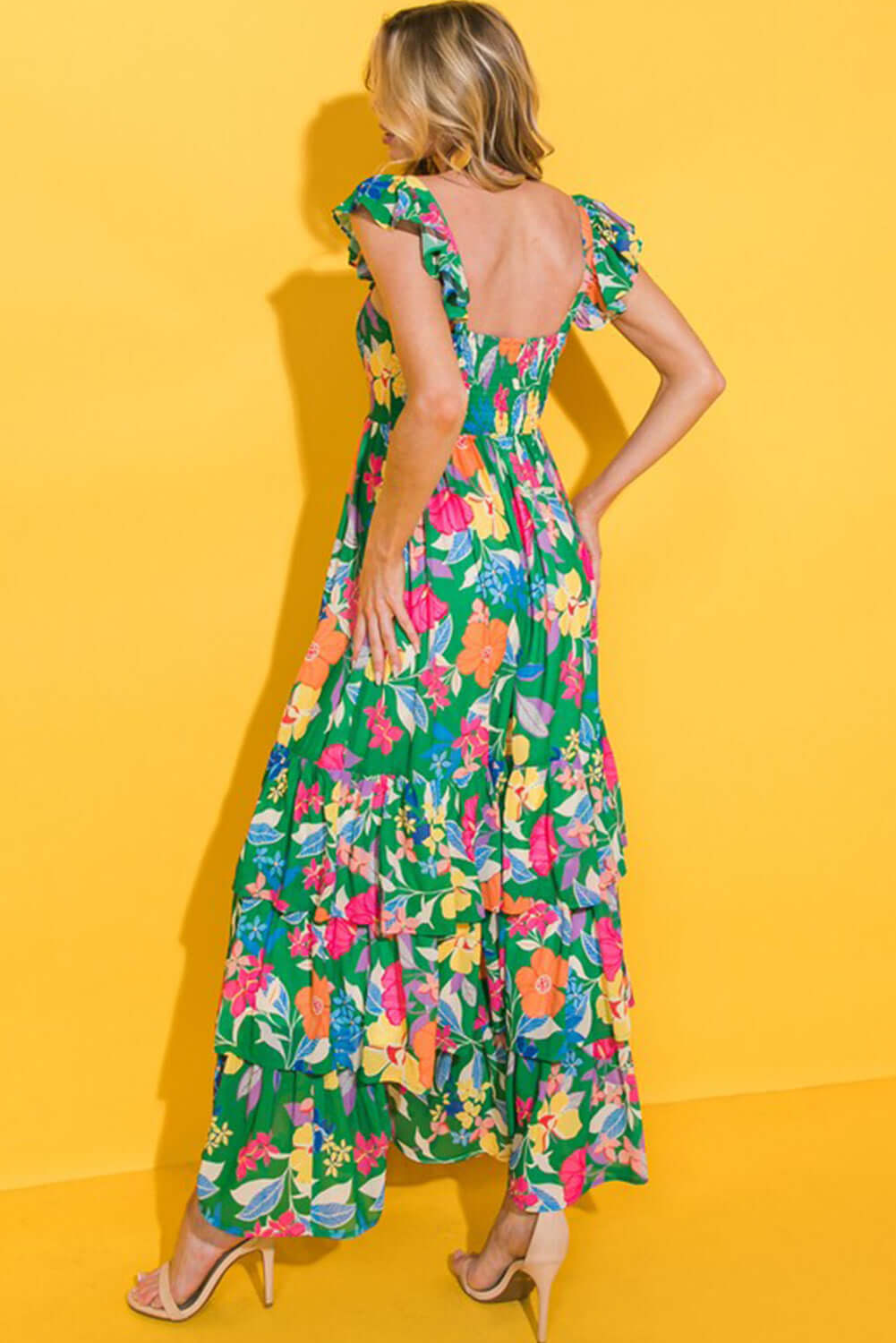 Back view of Summer Symphony Dress featuring vibrant floral print and ruffled shoulder straps against a yellow backdrop.
