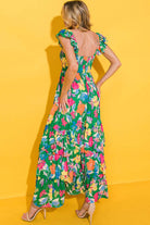 Back view of Summer Symphony Dress featuring vibrant floral print and ruffled shoulder straps against a yellow backdrop.