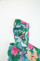 Close-up of a vibrant floral print dress featuring ruffles and green fabric, perfect for summer days.