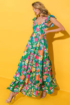 Bright floral maxi dress with ruffled straps, perfect for summer twirls against a vibrant yellow backdrop.