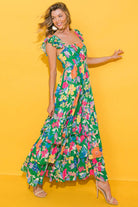 Model wearing the vibrant Summer Symphony Dress with bold floral prints against a yellow background.