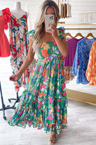 Model wearing the Summer Symphony Dress, a green floral maxi with ruffled straps and tiered design, perfect for sunny days.