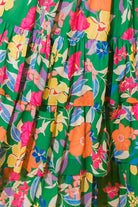 Vibrant floral print on a tiered maxi dress with ruffles, featuring bold colors of pink, coral, and green.