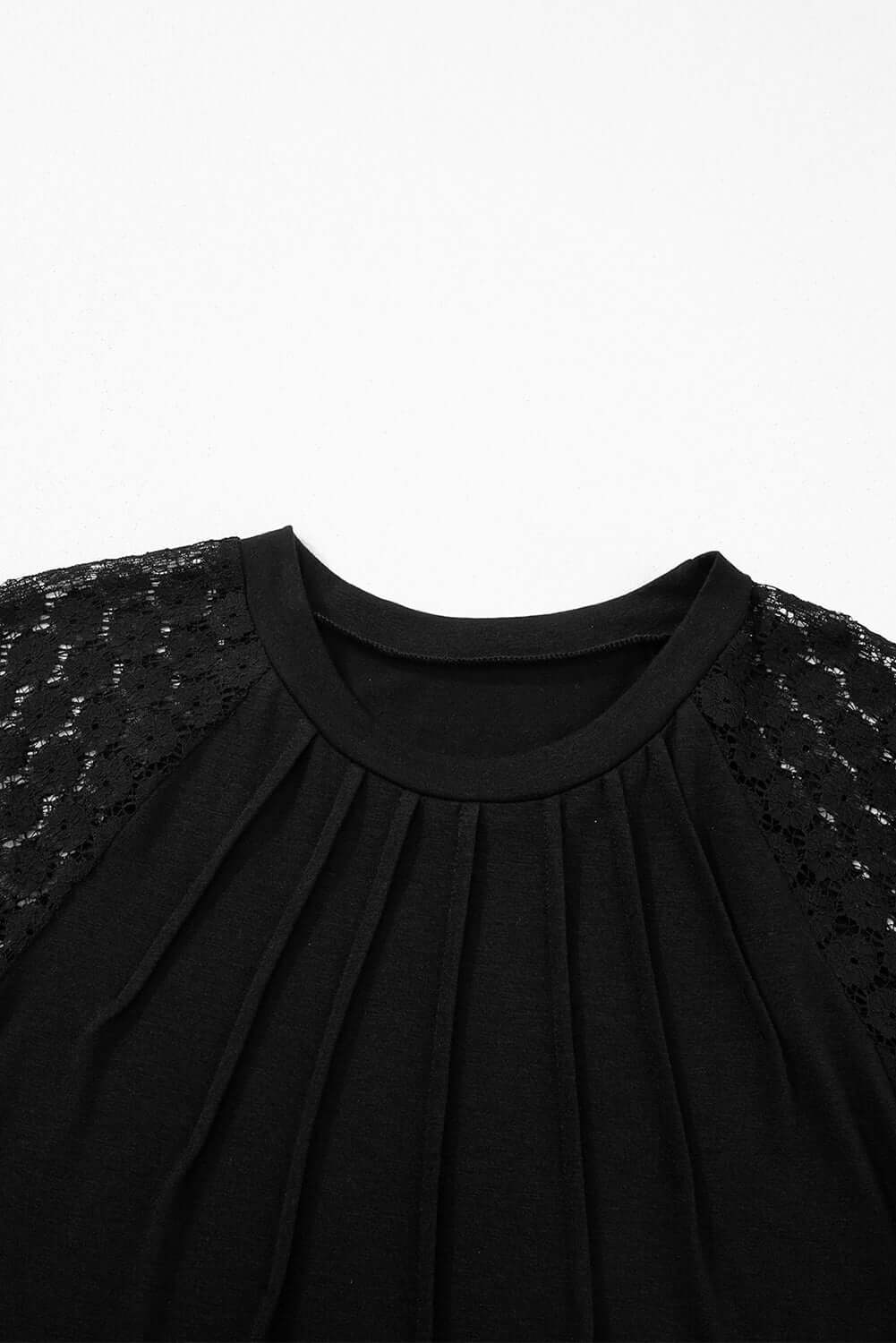 Close-up of Shadow Luxe Dress featuring pleated neckline and lace raglan sleeves in a chic black design.