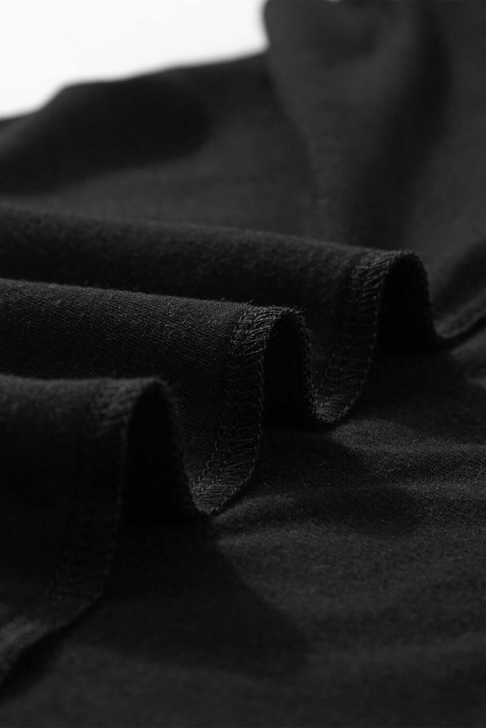 Close-up of soft black fabric with gentle pleats, showcasing texture and quality for the Shadow Luxe Dress.