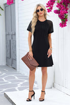 Chic black Shadow Luxe Dress with lace sleeves, pleated neckline, and stylish sandals, perfect for any occasion.