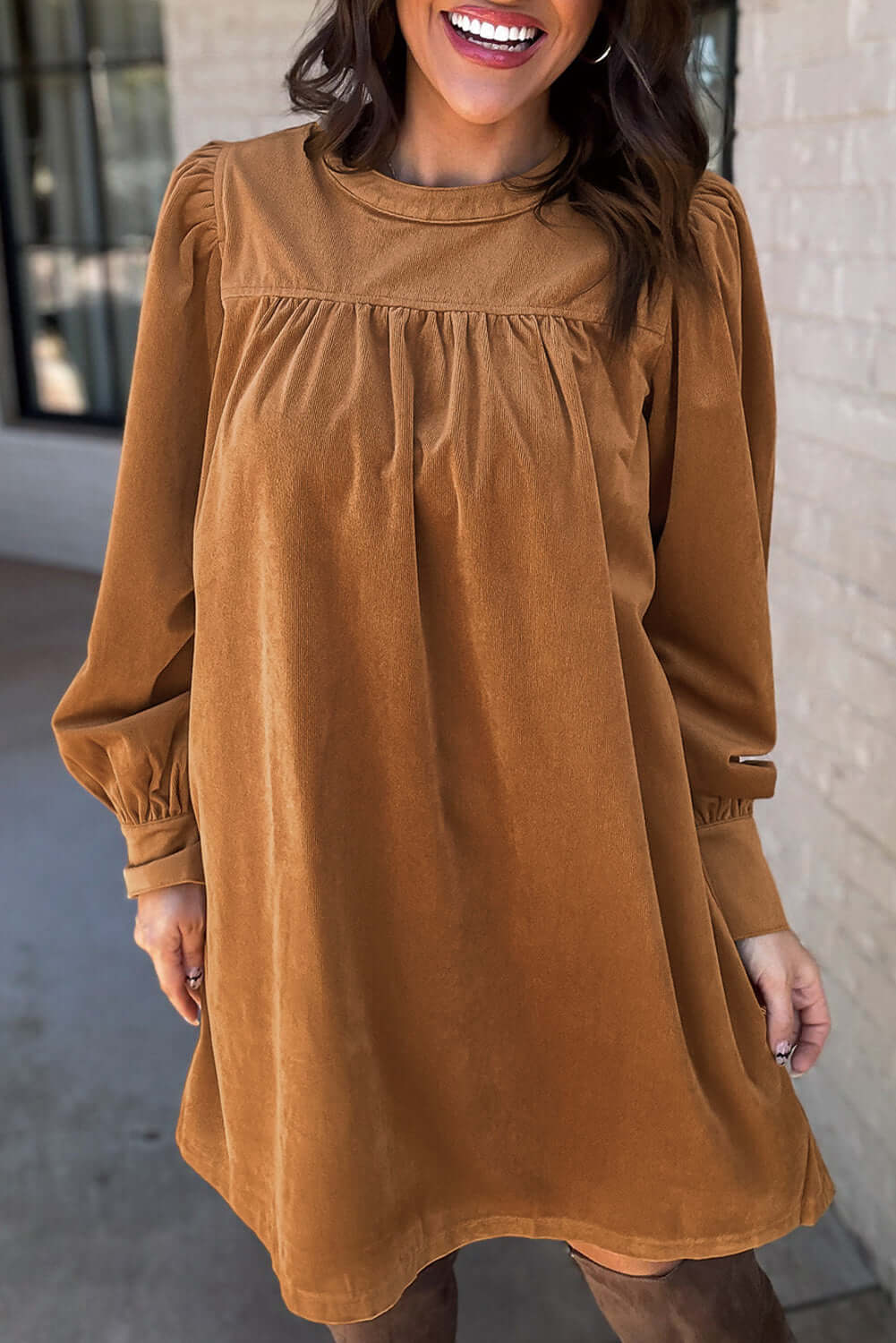 Woman wearing a copper corduroy dress with pleats and puff sleeves, exuding luxury and sophistication, perfect for a flattering silhouette.