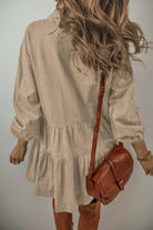 Woman wearing VENTURE OUT mini dress in Desert Tan with puff sleeves and pleated design, paired with brown crossbody bag.