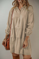 Elegant VENTURE OUT Desert Tan mini dress with puff sleeves, buttoned front, and tiered design, styled with a brown bag.