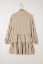 Desert Tan VENTURE OUT Dress with pleated and tiered design and puff sleeves on a hanger, back view.