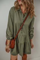 Woman wearing VENTURE OUT dress in Jungle Green with puff sleeves and tiered pleats, accessorized with a brown shoulder bag.