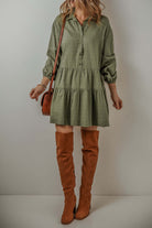 Woman wearing VENTURE OUT Dress in Jungle Green with puff sleeves, tiered pleats, and brown knee-high boots.