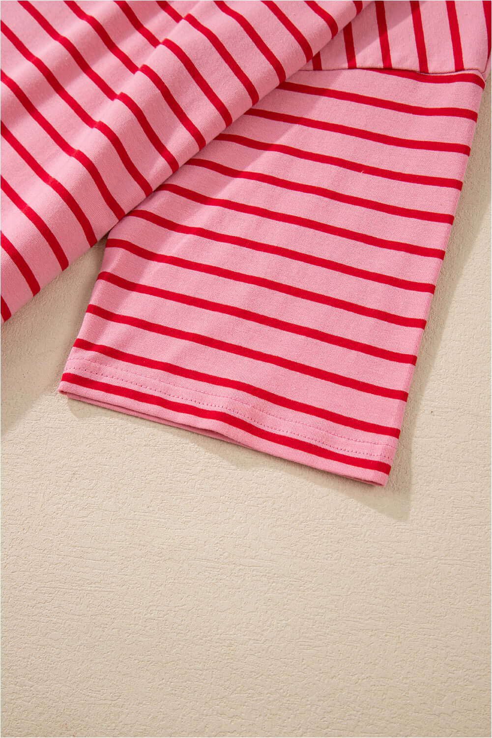 Close-up of striped fabric in pink and red for the Strawberry Sundays Dress, highlighting its chic design.