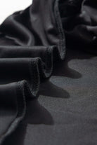 Close-up of luxurious black velvet fabric with folded edges, showcasing the smooth and silky texture of the SABLE SIREN Dress.