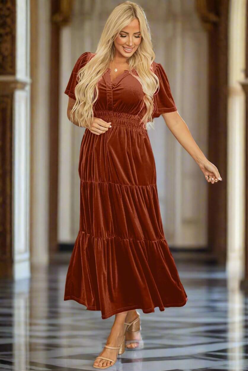 Woman in copper velvet maxi dress with shirred waist and tiered design from Vivian-Lu, perfect for elegant occasions.