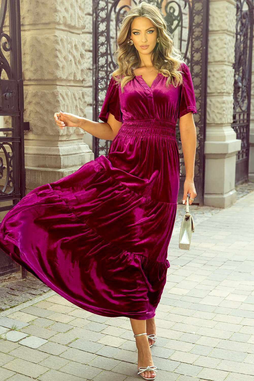 Woman in a velvet maxi dress with short sleeves and V-neckline, showcasing boho-inspired tiered design and elegant style.