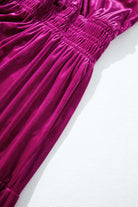 Close-up of a vibrant magenta velvet dress with shirred details and flowing fabric, showcasing texture and elegant design.