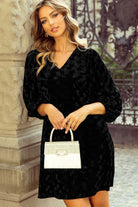 Woman wearing Velvet Eclipse Dress with muted animal print and V-neck, holding a handbag.