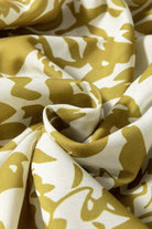 Close-up of soft fabric with a floral pattern in golden and white tones, ideal for springtime fashion.