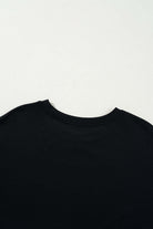 Close-up of the neckline and back of a black T-shirt on a light background.