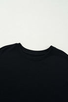 Black t-shirt close-up showcasing round neckline and soft fabric texture. Perfect for casual and versatile styling.