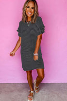 Model wearing the Perfect Pathways black stripe mini t-shirt dress with ruffle sleeves in front of a pink wall.